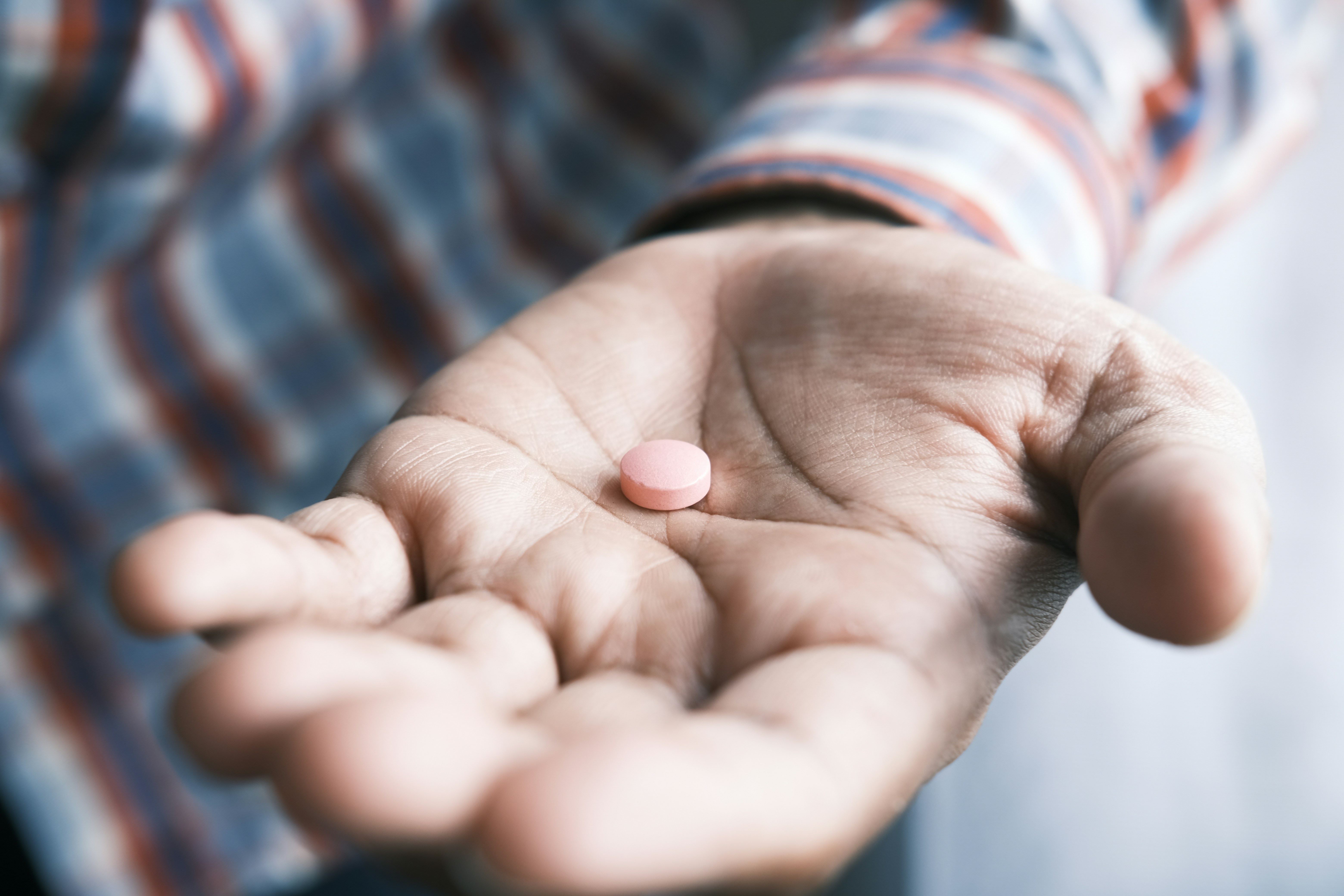 a hand holding a pill